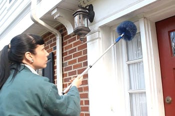 Pest control technician treating windows outside a home - Keep pests away from your home with Cooper Pest Control in PA and NJ